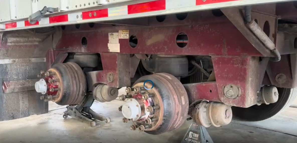 Trailer axles and air suspension with wheels removed, exposing brake drums and wheel ends